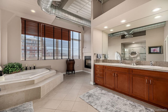 bathroom with a shower stall, a fireplace, a sink, and tile patterned floors