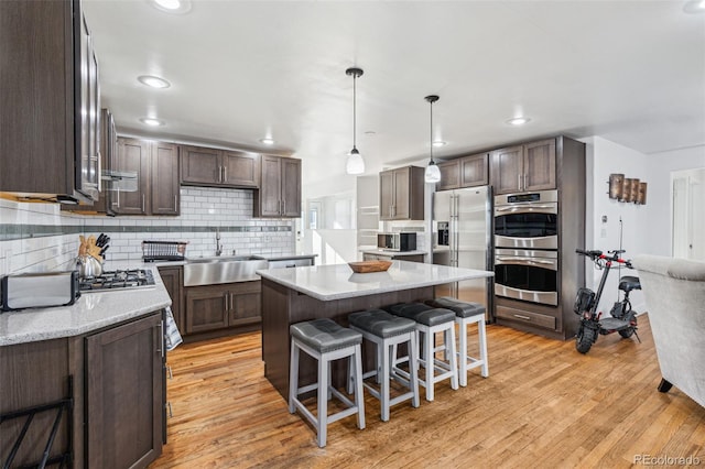 kitchen featuring pendant lighting, appliances with stainless steel finishes, sink, a center island, and decorative backsplash