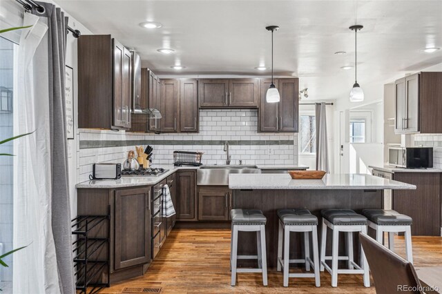 kitchen with sink, a breakfast bar area, a center island, and pendant lighting