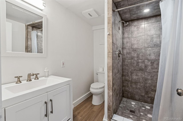 bathroom featuring hardwood / wood-style flooring, toilet, walk in shower, and vanity