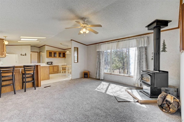 1360 Kiowa Rd, Florissant, CO 80816 - living room featuring a wood stove, crown molding, vaulted ceiling, a ceiling fan, and carpet floors