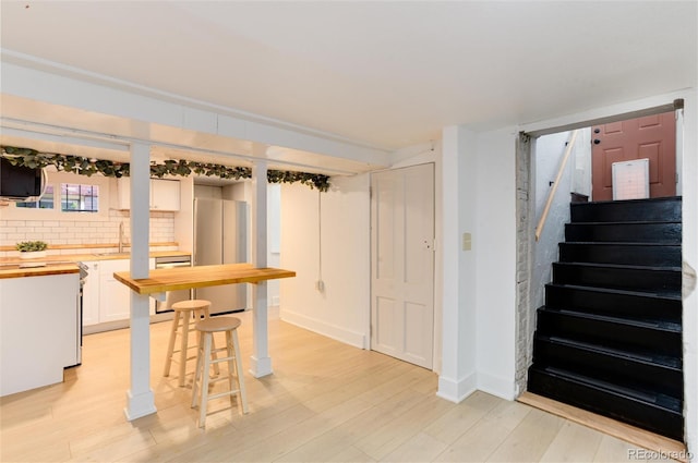 260 N Grant St, Denver, CO 80203 - basement featuring freestanding refrigerator, light wood-style flooring, a sink, and stairway