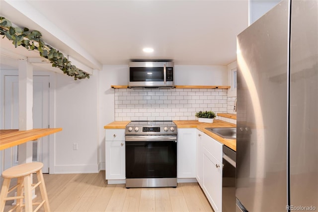 260 N Grant St, Denver, CO 80203 - kitchen featuring stainless steel appliances, butcher block counters, open shelves, backsplash, and white cabinetry