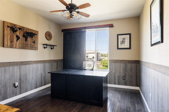 office with wainscoting, dark wood-style floors, ceiling fan, wood walls, and baseboards