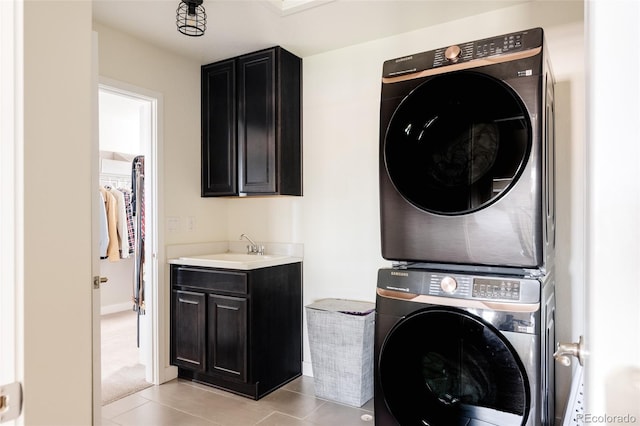 laundry area with stacked washing machine and dryer, cabinet space, and light tile patterned floors