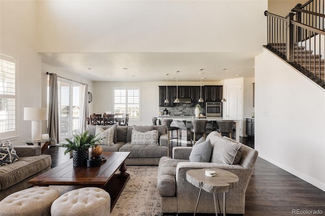 living room featuring dark wood finished floors, baseboards, stairs, and a high ceiling