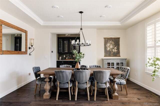dining space featuring crown molding, a chandelier, dark wood-style floors, baseboards, and a raised ceiling