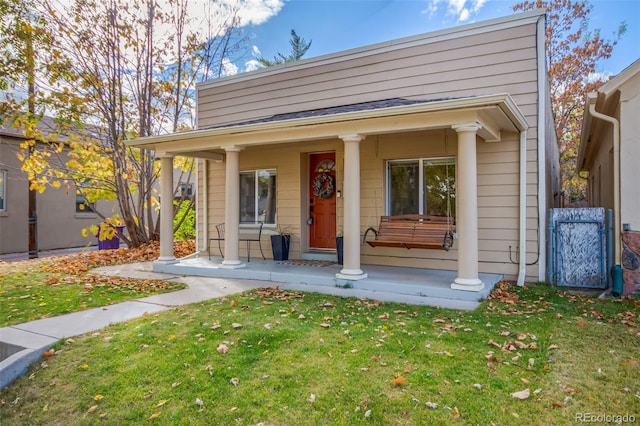 view of front of home featuring covered porch, a front yard, and a gate