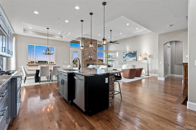 29303 E 165th Ave, Brighton, CO 80603 - kitchen featuring a tray ceiling, stainless steel dishwasher, ceiling fan, arched walkways, and open floor plan
