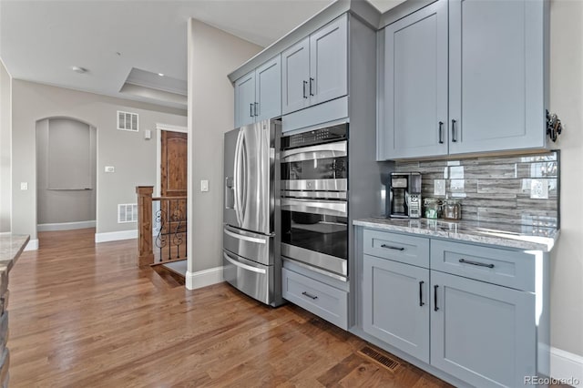 29303 E 165th Ave, Brighton, CO 80603 - kitchen with appliances with stainless steel finishes, arched walkways, light wood finished floors, backsplash, and light stone counters