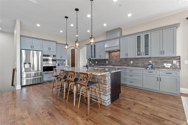 29303 E 165th Ave, Brighton, CO 80603 - kitchen featuring stainless steel appliances, gray cabinetry, a breakfast bar area, decorative backsplash, and a center island with sink