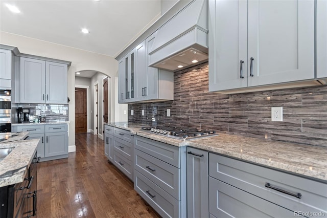 29303 E 165th Ave, Brighton, CO 80603 - kitchen featuring stainless steel appliances, gray cabinetry, arched walkways, backsplash, and light stone counters