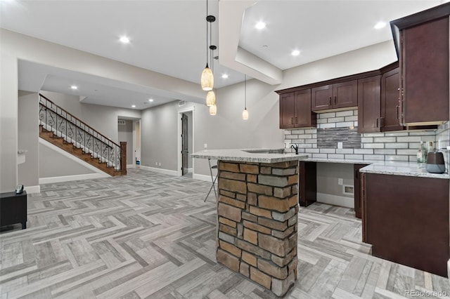 29303 E 165th Ave, Brighton, CO 80603 - kitchen featuring backsplash, decorative light fixtures, dark brown cabinets, light stone counters, and open floor plan