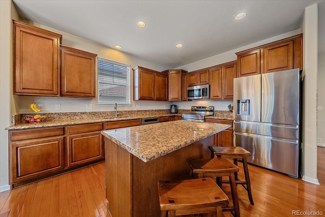 6461 S Ider St, Aurora, CO 80016 - kitchen featuring stainless steel appliances, a sink, brown cabinetry, a kitchen island, and recessed lighting
