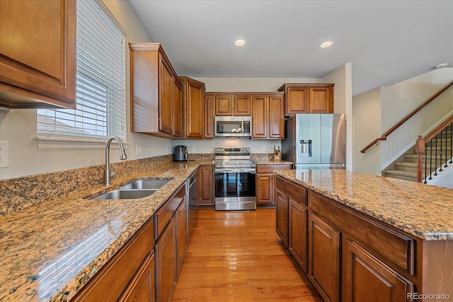 6461 S Ider St, Aurora, CO 80016 - kitchen with stainless steel appliances, a sink, light wood-type flooring, brown cabinetry, and light stone countertops