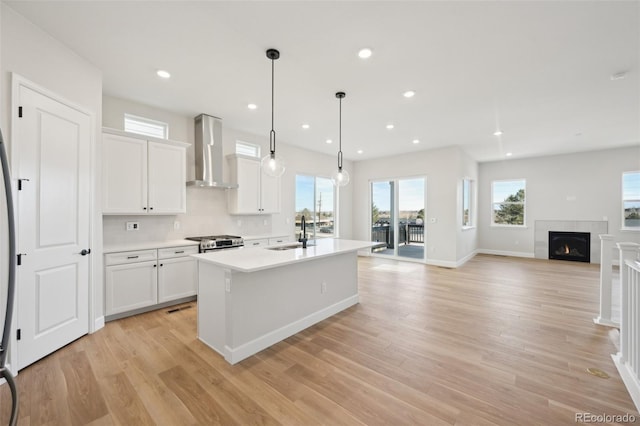 kitchen with white cabinetry, sink, wall chimney exhaust hood, and light wood-type flooring