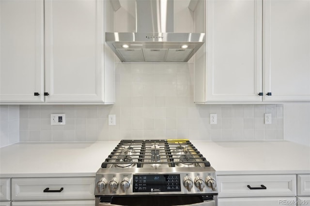 kitchen with tasteful backsplash, white cabinets, wall chimney exhaust hood, and stainless steel stove