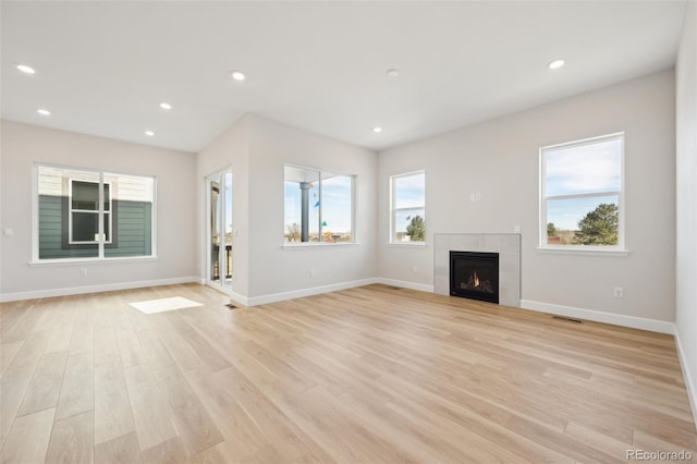 unfurnished living room with light hardwood / wood-style floors and a tile fireplace