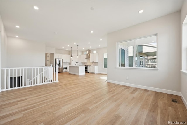 unfurnished living room with sink and light hardwood / wood-style floors