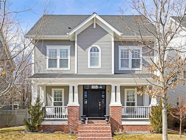 craftsman inspired home featuring a shingled roof, fence, a porch, and brick siding