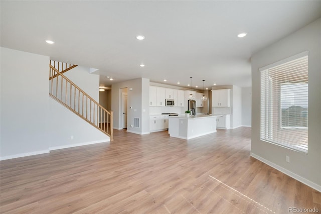 954 Plum Creek Ct, Brighton, CO 80601 - unfurnished living room with stairs, recessed lighting, and light wood-type flooring