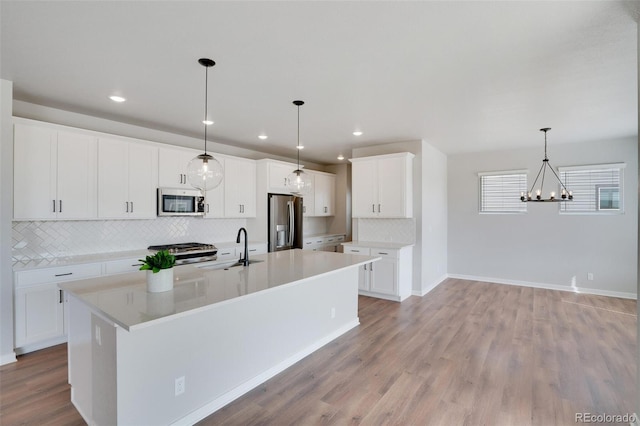954 Plum Creek Ct, Brighton, CO 80601 - kitchen with appliances with stainless steel finishes, backsplash, light wood-style floors, a chandelier, and light countertops