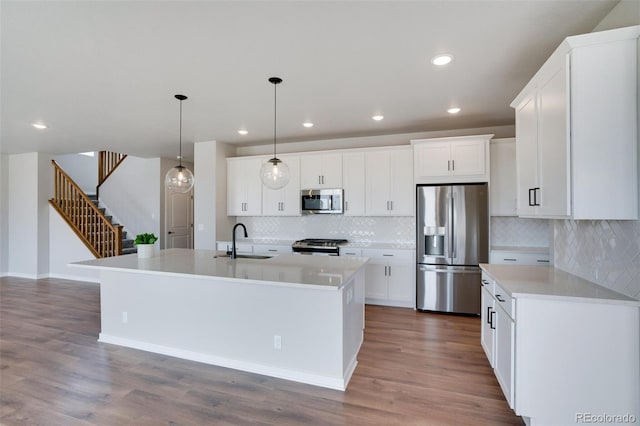 954 Plum Creek Ct, Brighton, CO 80601 - kitchen with stainless steel appliances, tasteful backsplash, wood finished floors, a kitchen island with sink, and recessed lighting