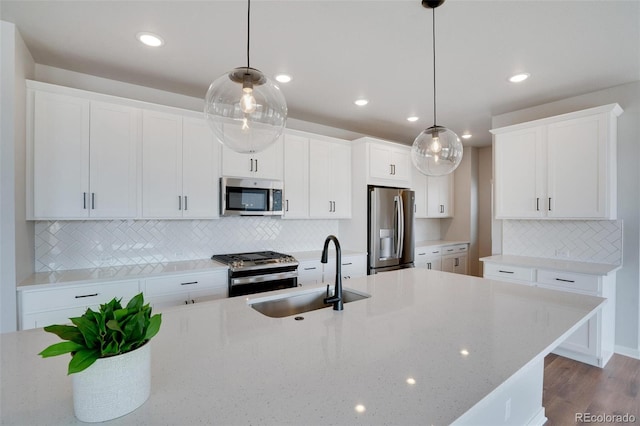 kitchen with appliances with stainless steel finishes, backsplash, sink, decorative light fixtures, and white cabinetry