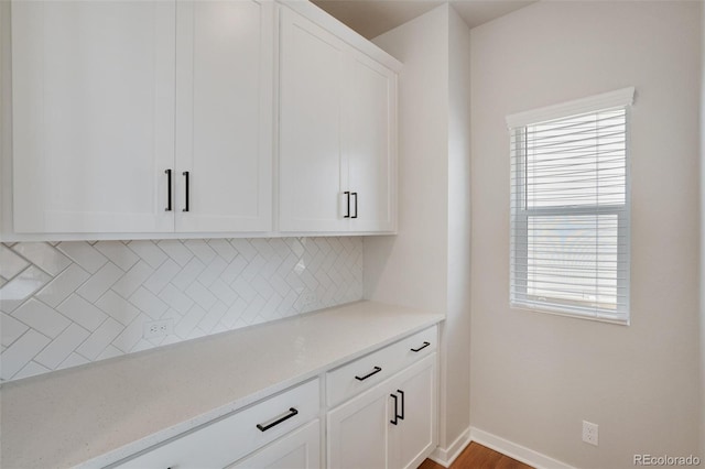 bar featuring backsplash, white cabinetry, and light stone counters