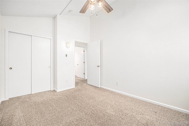 unfurnished bedroom with ceiling fan, high vaulted ceiling, carpet, and a closet