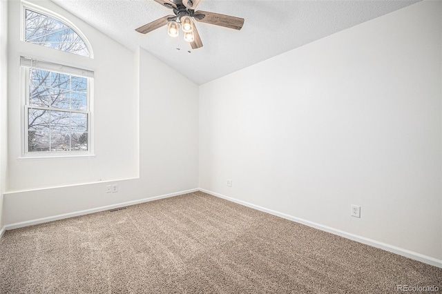 carpeted empty room featuring a textured ceiling, vaulted ceiling, and ceiling fan