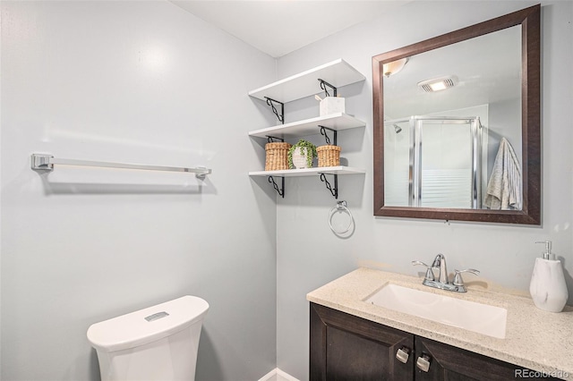 bathroom featuring vanity, a shower with door, and toilet