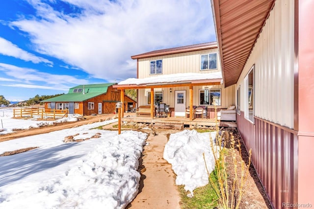 snow covered back of property with covered porch