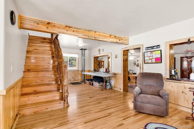 sitting room with light hardwood / wood-style floors, ceiling fan, and wood walls