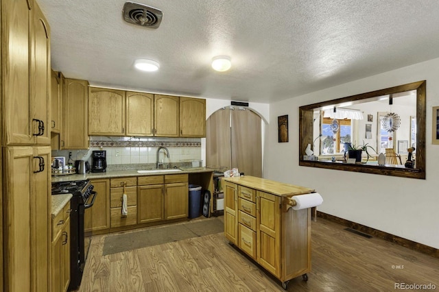 kitchen featuring a textured ceiling, black range, dark wood-type flooring, and sink