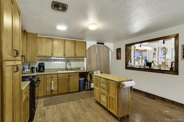 68600 State Highway 69, Westcliffe, CO 81252 - kitchen featuring black range with gas stovetop, wood finished floors, light countertops, decorative backsplash, and a textured ceiling