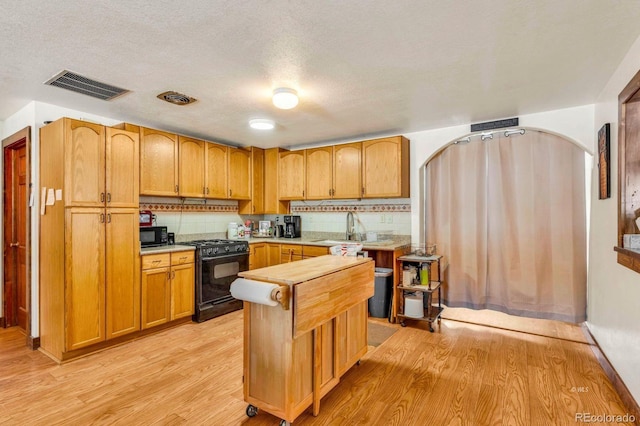 68600 State Highway 69, Westcliffe, CO 81252 - kitchen featuring black appliances, decorative backsplash, light wood finished floors, a textured ceiling, and arched walkways