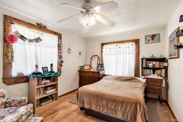 bedroom featuring ceiling fan, light hardwood / wood-style floors, and a textured ceiling