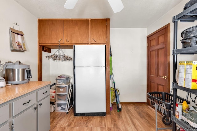 kitchen featuring ceiling fan with notable chandelier, white fridge, a textured ceiling, and light hardwood / wood-style flooring