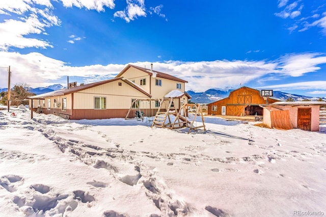 snow covered house featuring a mountain view and an outbuilding