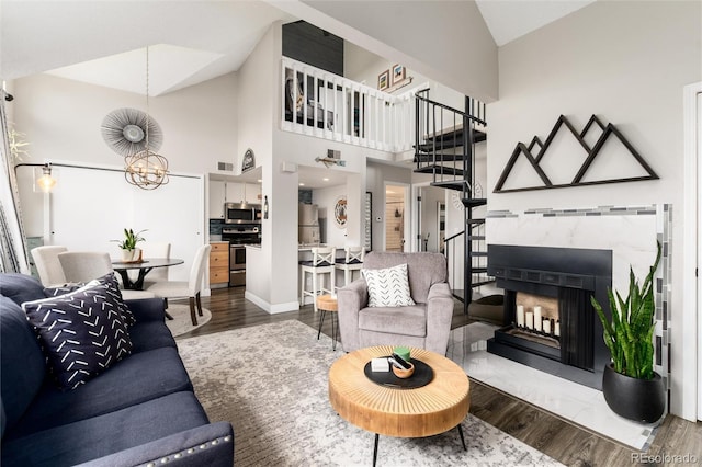 8311 S Upham Way Unit 1-207, Littleton, CO 80128 - living room featuring wood finished floors, a premium fireplace, a chandelier, stairs, and high vaulted ceiling