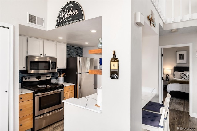 8311 S Upham Way Unit 1-207, Littleton, CO 80128 - kitchen with stainless steel appliances, dark wood-style flooring, white cabinetry, decorative backsplash, and light stone counters