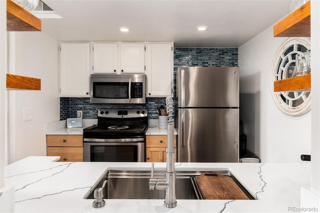 8311 S Upham Way Unit 1-207, Littleton, CO 80128 - kitchen with stainless steel appliances, backsplash, light stone countertops, white cabinets, and recessed lighting