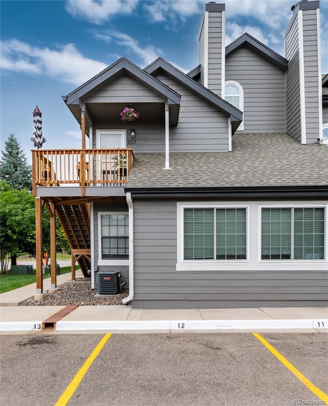 8311 S Upham Way Unit 1-207, Littleton, CO 80128 - view of front of house with roof with shingles, uncovered parking, a deck, and stairway