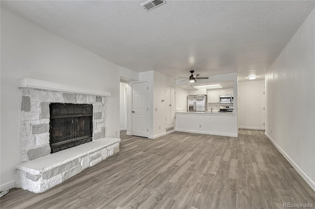4283 S Salida Way Unit 8, Aurora, CO 80013 - unfurnished living room with wood finished floors, ceiling fan, a fireplace, and a textured ceiling