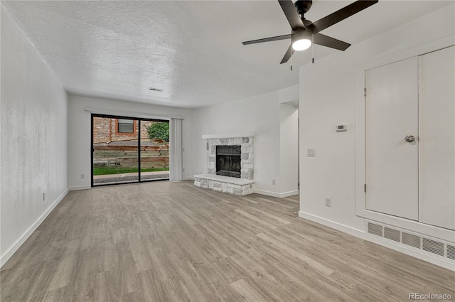 4283 S Salida Way Unit 8, Aurora, CO 80013 - unfurnished living room featuring light wood-type flooring, ceiling fan, a fireplace, and a textured ceiling