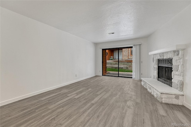 4283 S Salida Way Unit 8, Aurora, CO 80013 - unfurnished living room featuring light wood-style flooring, a textured ceiling, and a stone fireplace