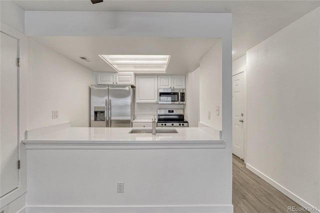 4283 S Salida Way Unit 8, Aurora, CO 80013 - kitchen with appliances with stainless steel finishes, a peninsula, wood finished floors, light countertops, and white cabinets
