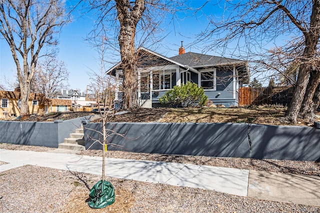 exterior space featuring a porch, fence, and a chimney