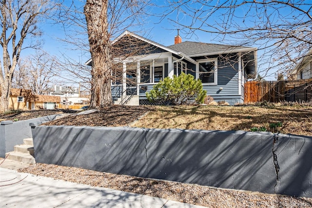 exterior space with a shingled roof, fence, and a chimney